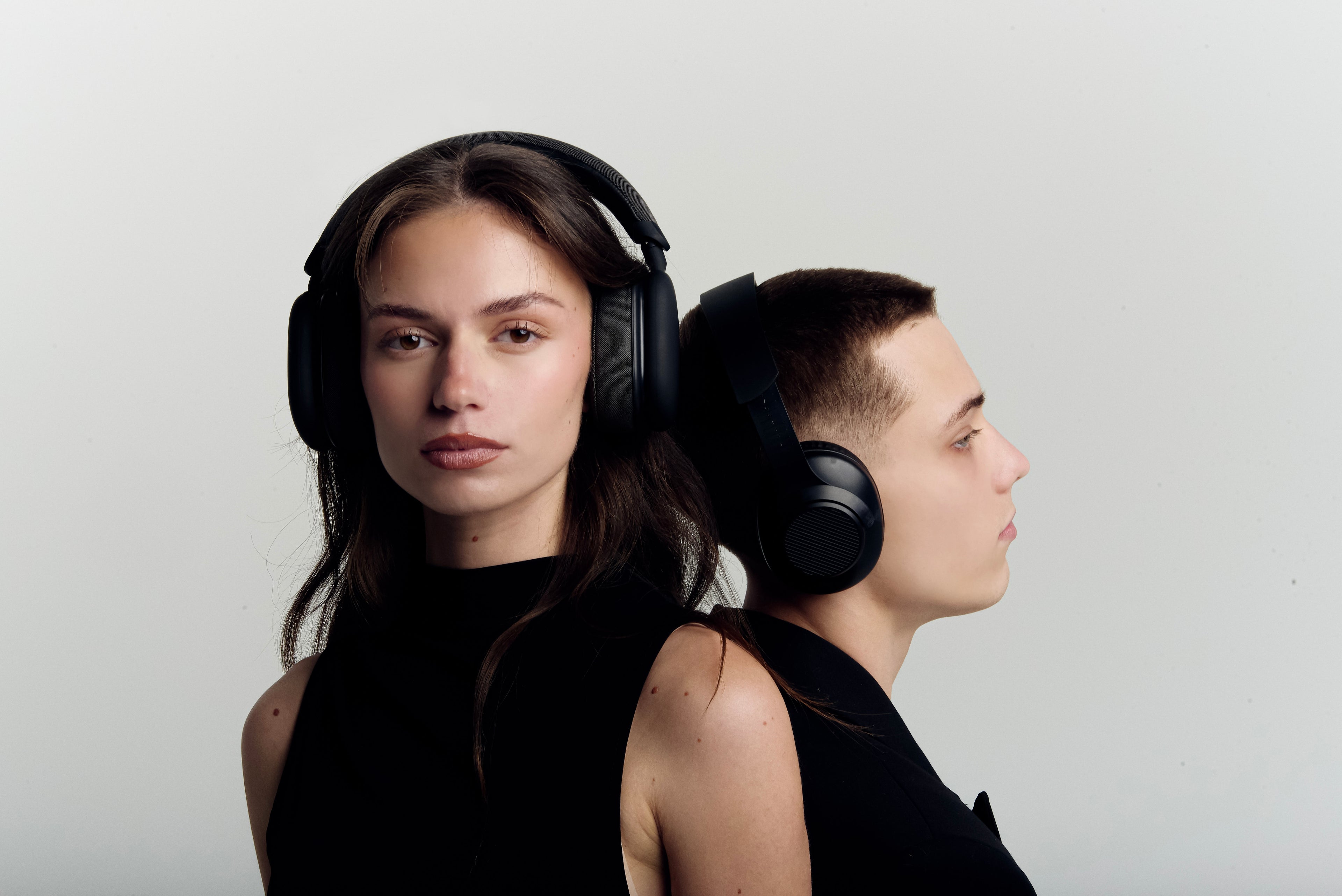 Two people wearing large black Adda Collins headphones against a plain background